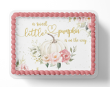 Baby shower cake with pumpkins, flowers, and text 'a sweet little pumpkin is on the way' on a white background.