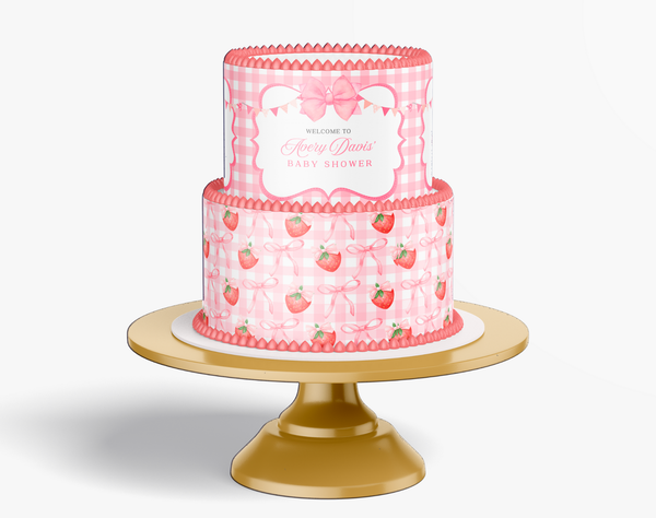 Pink baby shower cake with strawberry pattern on a gold stand against a white background
